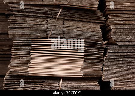 Large stacks of uniform cardboard sheets neatly arranged for recycling or packaging. Warehouse of corrugated cardboard boxes stacked Stock Photo
