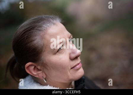 A sad beautiful middle-aged woman's hair is starting to turn gray and she's worried about it. The woman needs to start coloring her hair Stock Photo