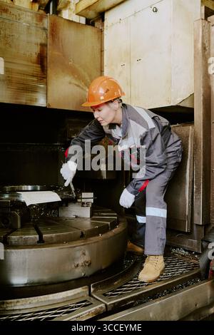 Young Adult Caucasian Woman Operating Industrial Machinery in Factory Setting Stock Photo