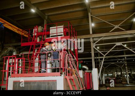 Two Young Adult Caucasian Engineers Inspecting Industrial Machinery Indoors Stock Photo