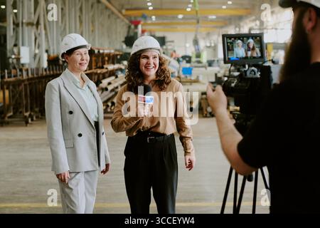 Caucasian Young Adult Woman Interviewing Middle Aged Woman at Industrial Facility Stock Photo