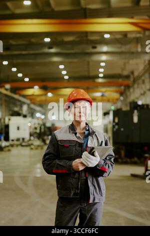 Middle Aged Caucasian Woman Engineer Holding Tablet Standing in Factory Stock Photo