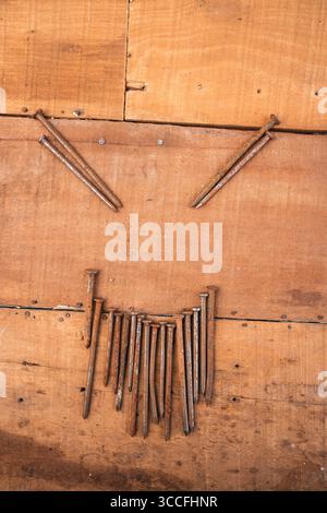 Rusty nails on wood. Close-up of worn planks and variously shaped metal fasteners. Stock Photo