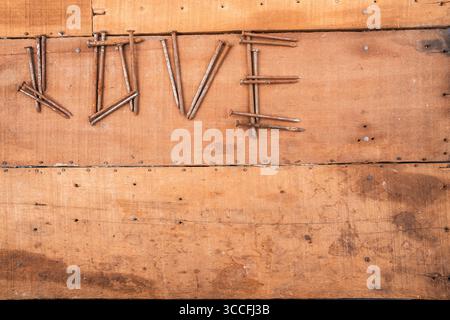 Rusty nails on wood. Close-up of worn planks and variously shaped metal fasteners. Stock Photo