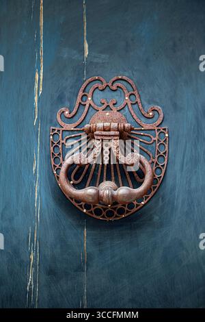 Old bronze knocker on a blue wooden door Stock Photo