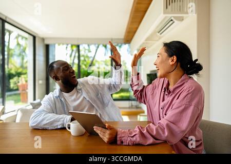 Multicultural couple working remotely, planning finances and investments. Digital nomad lifestyle Stock Photo