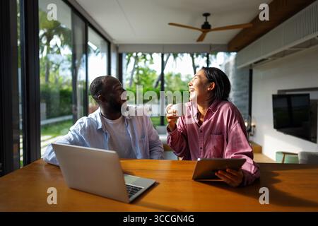 Multicultural couple working remotely, planning finances and investments online. Digital lifestyle Stock Photo