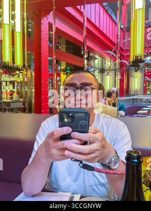 Paris, France, Chinese Tourist using Smart Phone, at Tables, inside French Bistro Restaurant, "Maslow - Temple » Marais paris restaurant Stock Photo