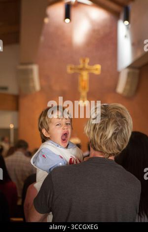 April 24, 2016: A four year old boy yawns with boredom on his father's shoulder during mass at a Laguna Niguel, CA, Catholic church. Note cross in background. (Credit Image: © Spencer Grant/ZUMA Press Wire) Stock Photo
