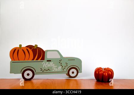A decorative truck carrying pumpkins stands next to a pumpkin candle Stock Photo