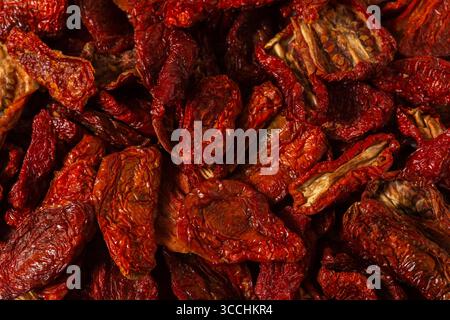 Macro close-up of sun-dried tomatoes, showing their vibrant red color, natural wrinkles, and rich texture, perfect for Mediterranean cuisine and gourm Stock Photo