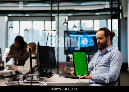 Startup office engineer using green screen tablet, developing artificial intelligence models for business analytics. IT specialist using mockup device, running simulations for AI forecasting Stock Photo