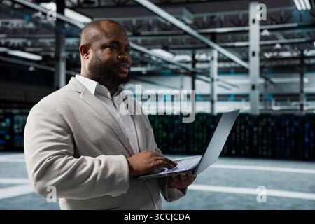 Engineer in server farm auditing systems for vulnerabilities, checking recovery plan. Data center IT specialist troubleshooting connectivity issues, making sure rigs are functioning optimally Stock Photo
