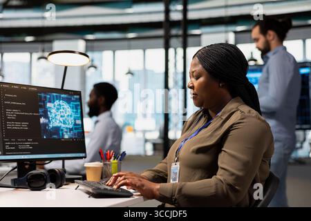 Software engineer using AI automation in tech workspace, building digital solutions. African american IT specialist working on PC to identify and fix bugs using artificial intelligence tools Stock Photo