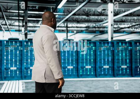 System administrator working in data center overseeing international user traffic. IT expert walking in server farm workplace hosting websites and delivering web content to online customers Stock Photo