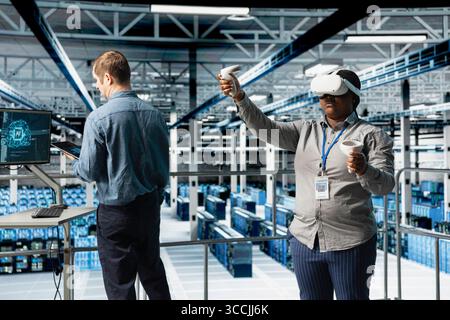 Teamworking server farm programmers using VR headset, running AI simulations. African american woman and coworker in data center using virtual reality technology to visualize neural networks Stock Photo