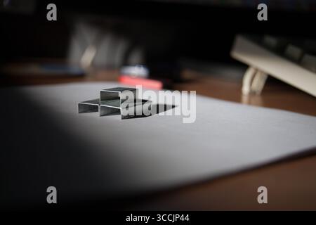 Black geometric forms made of staples placed on a white surface lit from the side Stock Photo