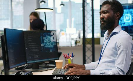 Computer scientist using AI on computer to optimize performance and forecast issues. African american worker in office training machine learning models using PC, camera A Stock Photo