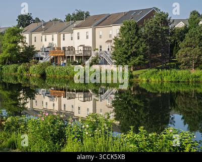 A row of modern townhouses beautifully reflected on the still waters of a lake in Ashburn Village, Virginia. Stock Photo