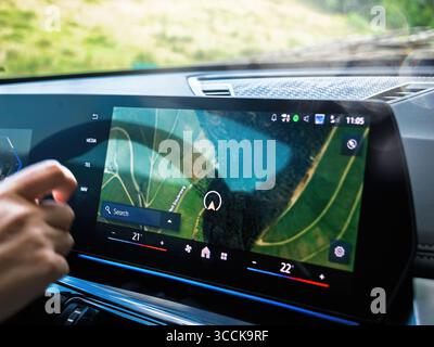 Durbach, Germany - Sep 15, 2024: Close-up of a BMW digital dashboard showing GPS navigation map with hand nearby, displaying navigation interface and Stock Photo