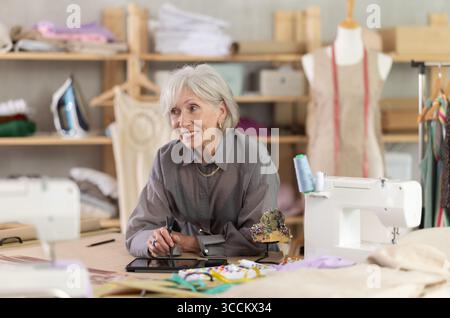 Woman dressmaker makes pattern using tablet Stock Photo