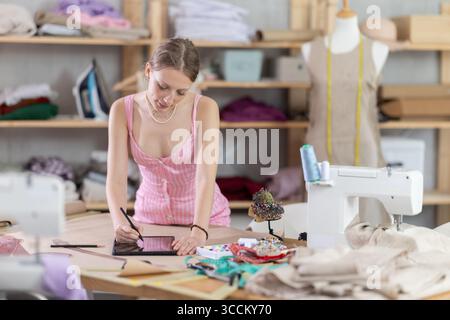 Woman dressmaker makes pattern using tablet Stock Photo