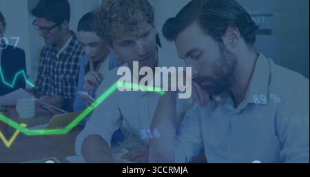 Two male analysts in blazers reviewing reports in conference room, examining paper charts Stock Photo
