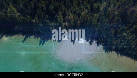 Evergreen forest meeting turquoise lake in remote aerial view, with grid and binary code overlay Stock Photo