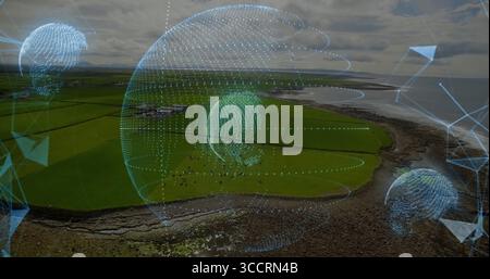 Hovering holographic sphere showing data globes above coast, with grazing herd and pasture fences Stock Photo