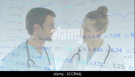 Standing doctors in scrubs and lab coat analyzing financial charts in clinic, with two stethoscopes Stock Photo