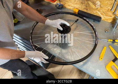 Unrecognizable male technician holding mountain bike wheel fixing tire in repair shop Stock Photo