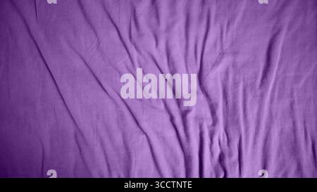 Photo of a fabric background. Uneven folds. More folds at the bottom of the background. Different shades of purple color. Gradient in the middle of the background, from dark edges to light middle. Stock Photo