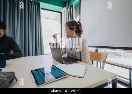 Colleagues collaborating in modern office space using laptops and digital devices Stock Photo