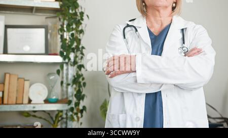 Confident Female Doctor Standing in Office Setting with Folded Arms Stock Photo
