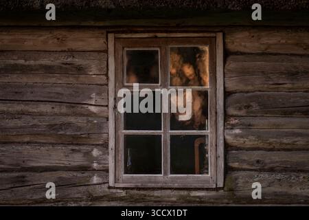 Rustic Log cabin and window with a reflection of sunrise. Old wooden log house window background. Stock Photo