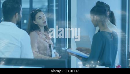Four colleagues discussing project plans in glass-walled office, with tablet, clipboard and papers Stock Photo