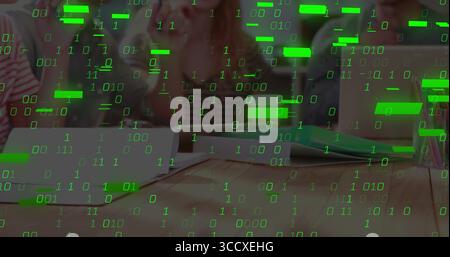 Collaborating students writing in notebooks and typing on laptop around wooden table, digital theme Stock Photo