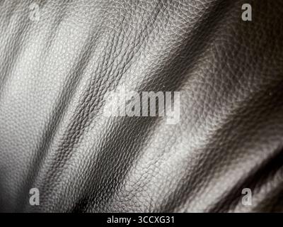 Black leather surface with a pattern. The surface is shiny and has a slight sheen. The pattern is visible on the surface and is made up of small lines Stock Photo