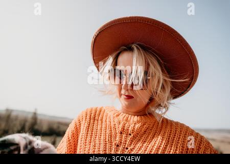 Woman in a Hat and Sunglasses Looking Down Stock Photo