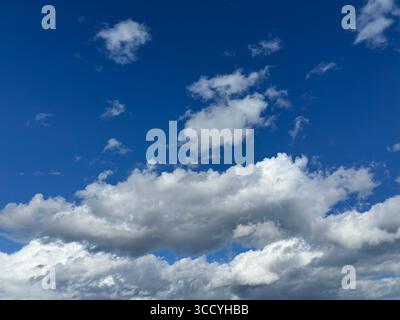 Bright blue sky filled with fluffy white clouds on a beautiful day. Stock Photo