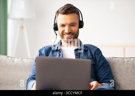 Relaxed man watching movie, using laptop and headphones Stock Photo