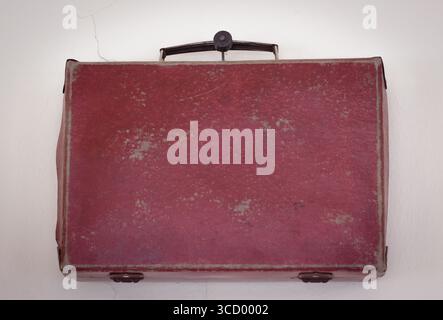 Vintage red suitcase on the wall Stock Photo
