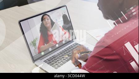 Taking notes senior man viewing printed report on laptop at conference table, with paper charts Stock Photo