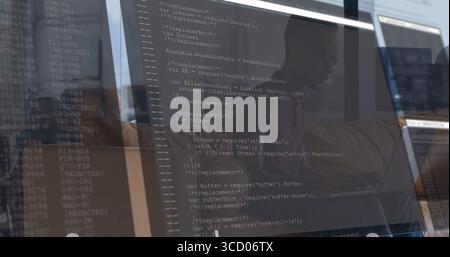 Developer wearing shirt and glasses typing code in office, with 3 screens showing JavaScript code Stock Photo