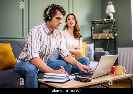Woman is angry because her man is working too much. Freelancer working from home. Stock Photo