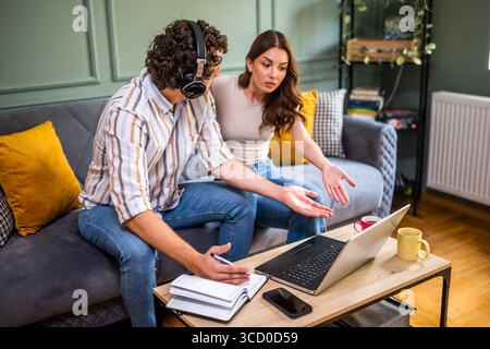 Woman is angry because her man is working too much. Freelancer working from home and arguing with his woman. Stock Photo