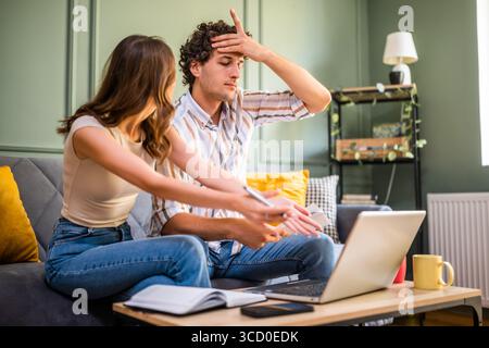 Couple checking home finance on laptop. They are in shock because of bad family budget. Stock Photo