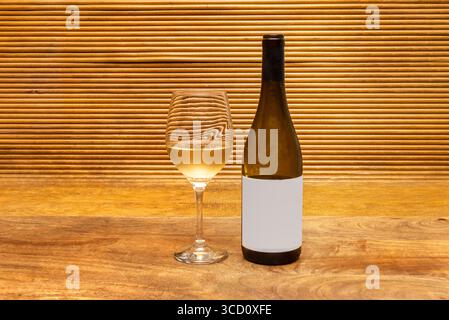 Minimalist composition of a half-full wine bottle and a finely carved glass Stock Photo