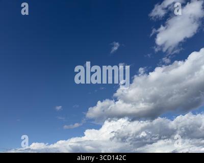 Beautiful daytime sky with fluffy white clouds against a vibrant blue. Stock Photo