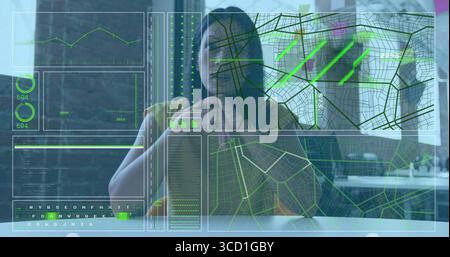 Analyzing data overlays by mature woman sipping from coffee mug at office desk, with map interfaces Stock Photo